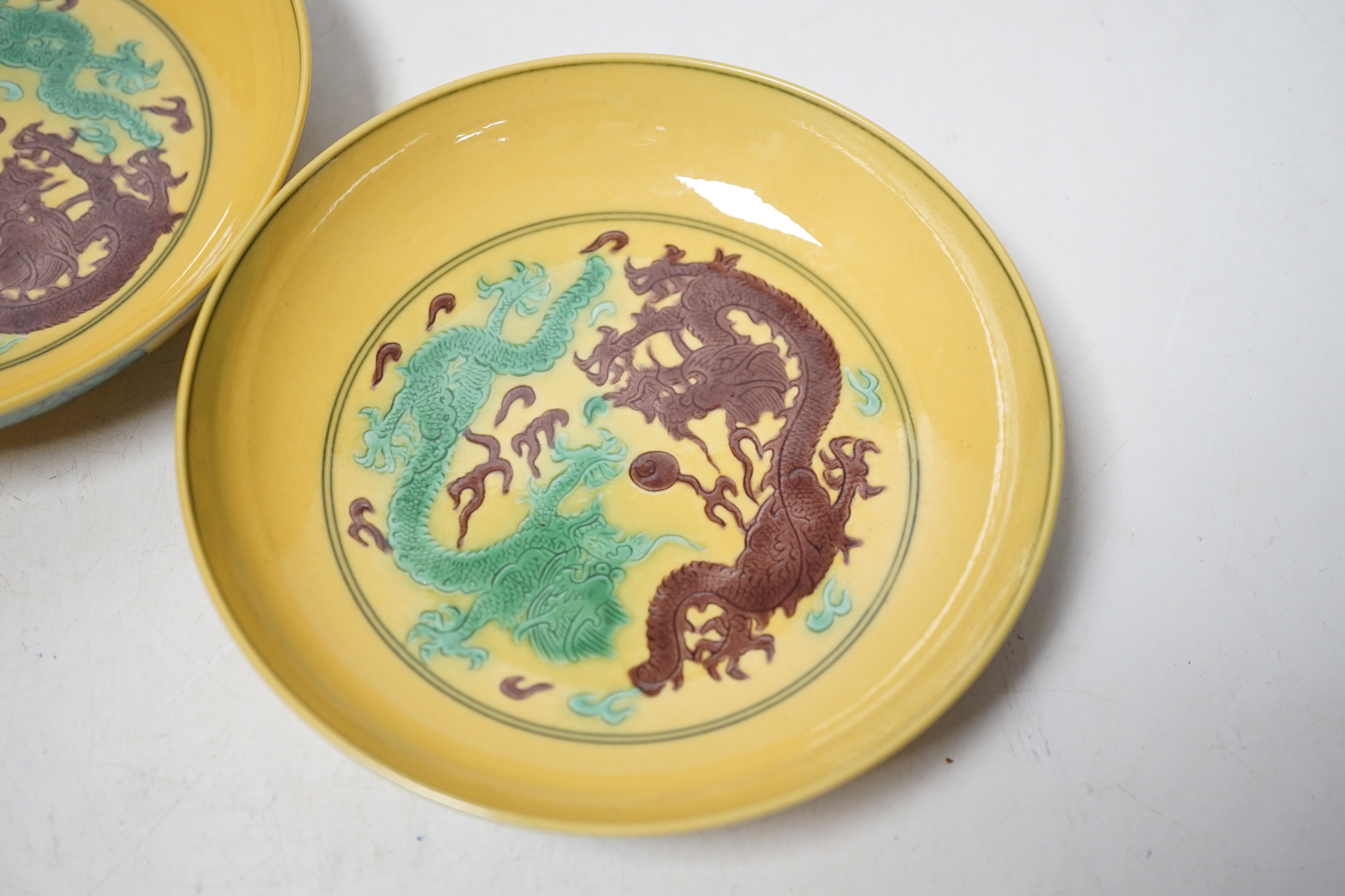 A pair of Chinese yellow glazed ‘dragon’ dishes, 13cm in diameter